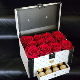 Open gift box with red roses and gold-wrapped chocolates