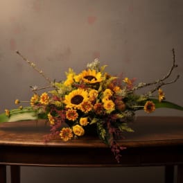 Sunflower and yellow rose arrangement in a low container with long branches