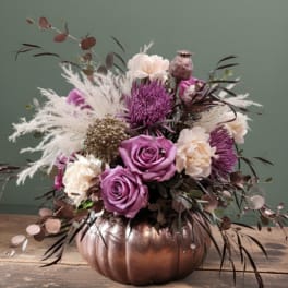 Purple and cream floral arrangement in a copper pumpkin vase