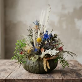 Pumpkin centerpiece with dried flowers, grasses, and blue accents