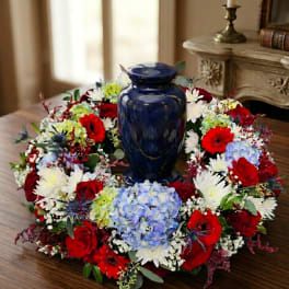 Floral wreath around a blue urn on a wooden table