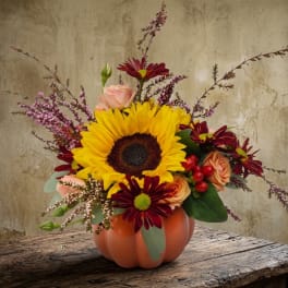 Sunflower and mixed flower arrangement in a pumpkin-shaped vase