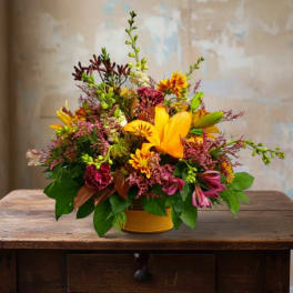 Bright mixed bouquet in a yellow container with orange lilies and pink blooms