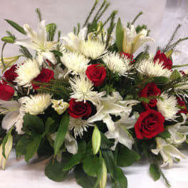 Red roses and white lilies arranged with white spider mums.