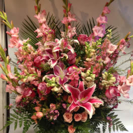 Large pink floral arrangement with lilies, roses, and tall gladiolus