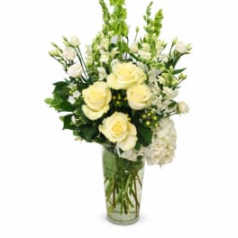 Cream roses and white flowers arranged in a clear glass vase