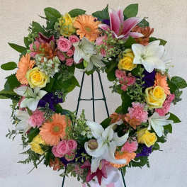 Colorful standing wreath of lilies, roses, gerbera daisies, and carnations on a metal easel