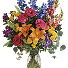 Colorful bouquet of roses, lilies, and snapdragons in a clear glass vase