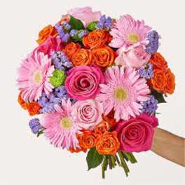 Handheld bouquet of pink daisies, orange roses, and purple filler flowers
