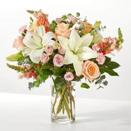 Bouquet of white lilies and peach roses in a clear glass vase