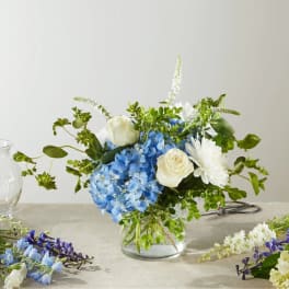 Blue hydrangeas and white roses in a clear glass vase