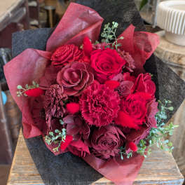 Bouquet of red roses and carnations wrapped in black and burgundy paper