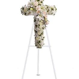 White floral cross arrangement on a standing easel