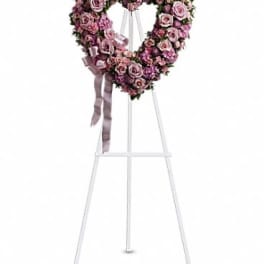 Heart-shaped pink rose wreath on a white easel with ribbon