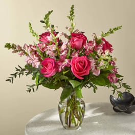 Pink roses and mixed pink flowers in a clear glass vase