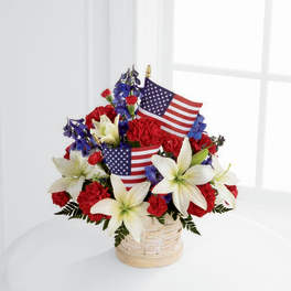 Basket arrangement of red carnations, white lilies, and small American flags