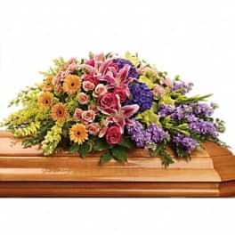 Colorful floral casket spray with pink lilies, roses, and purple blooms