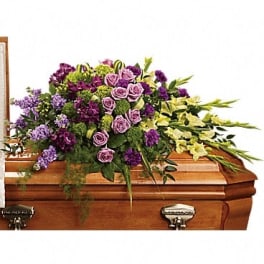 Purple and lavender floral spray on a wooden casket