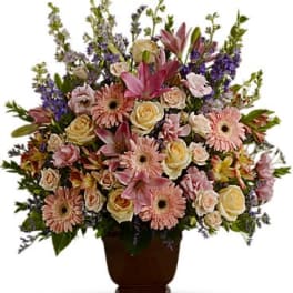 Mixed pink and cream flowers arranged in a dark urn vase