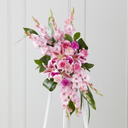 Pink floral standing spray with lilies and roses on a white easel