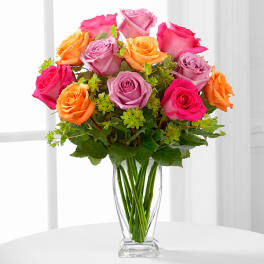 Bouquet of pink, lavender, and orange roses in a clear glass vase
