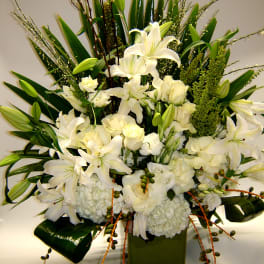 White lilies and roses arranged in a green square vase
