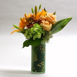 Orange lilies and peach roses arranged in a green vase