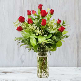 Medium bouquet of red roses with lush greenery in a clear glass vase