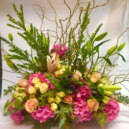 Large bouquet of pink hydrangeas, roses, and lilies with tall branches