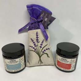 Two scented candles flank a lavender sachet gift bag.