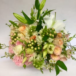 Bouquet of white lilies, peach roses, and pink blooms with green buds