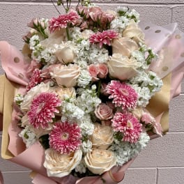 Bouquet of pink gerbera daisies and cream roses wrapped in pink paper