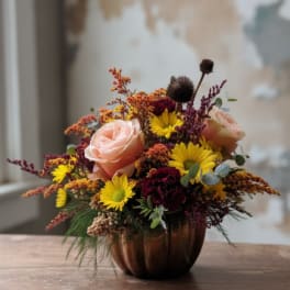 Mixed bouquet of roses and yellow daisies in a copper pumpkin vase
