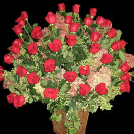 Large arrangement of red roses and pink hydrangeas in a rustic wooden container