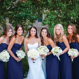 Bride and bridesmaids holding white bouquets outdoors