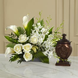 White roses and calla lilies arranged with orchids in a low container