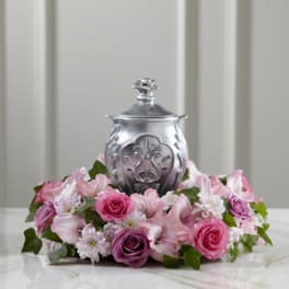 Pink and purple roses arranged around a silver urn