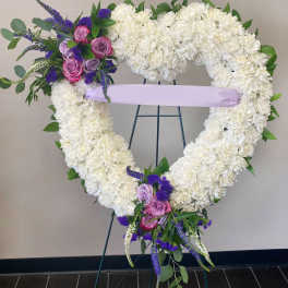Heart-shaped white floral wreath with pink and purple roses on an easel