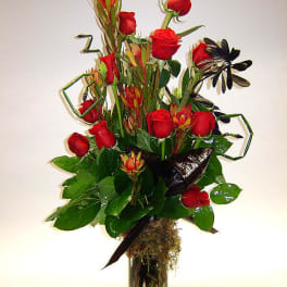 Tall bouquet of red roses and tropical flowers in a glass vase