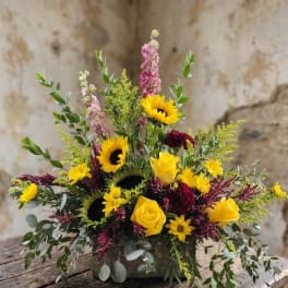 Mixed bouquet with yellow sunflowers and roses in a low container
