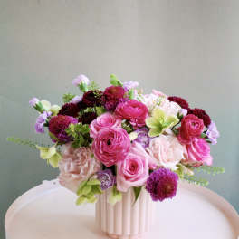 Pink and purple flower arrangement in a ribbed white vase