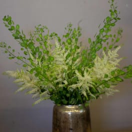White filler flowers and green stems in a metallic vase