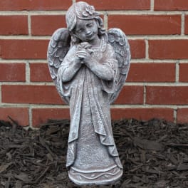 Stone angel statue standing against a brick wall