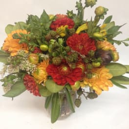 Mixed bouquet of red and orange flowers in a glass vase
