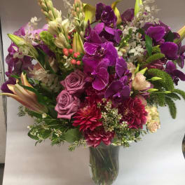 Purple orchid and rose bouquet in a clear glass vase