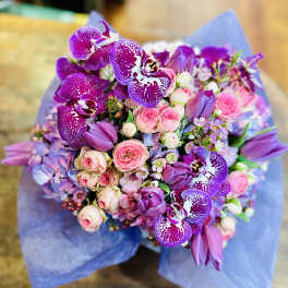 Bouquet of purple orchids and pink roses wrapped in blue paper