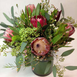 Bouquet of pink protea and greenery in a dark vase