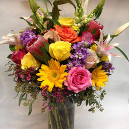 Mixed bouquet in a glass vase with roses, lilies, and sunflowers