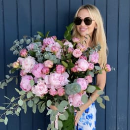 Woman holding a large bouquet of pink peonies and eucalyptus
