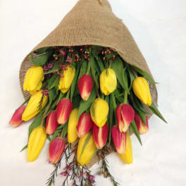 Bouquet of yellow and pink tulips wrapped in burlap